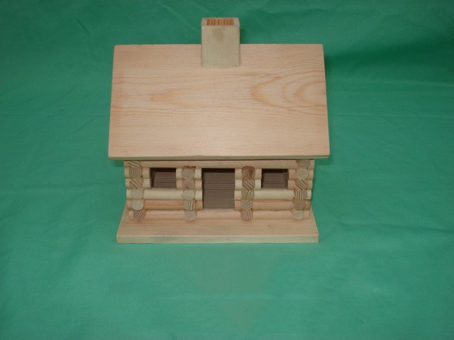 Log cabin style wooden bird house with chimney, log-stacked walls, side porches and central door