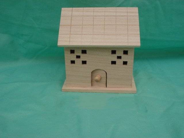 Square wooden bird house with shingled roof, small square window cutouts and arched door with knob