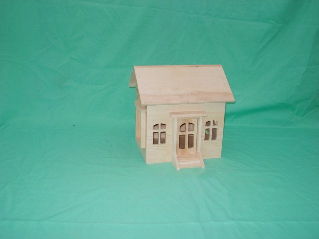 Cottage style wooden bird house with pitched roof, white-trim windows and central door with step