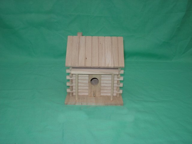 Fence-style wooden bird house with board-and-batten roof and single round entrance hole