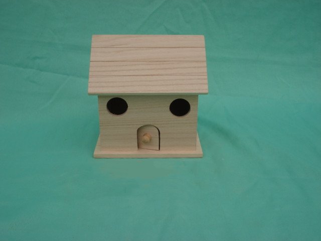 Simple wooden bird house with shingled roof, two round side holes and arched door with knob