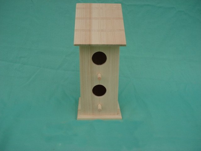 Tall two-story wooden bird house with tile roof and two stacked circular entrance holes