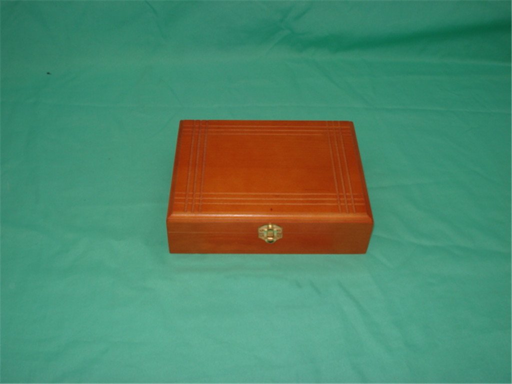 Square wooden box in orange cedar finish with incised concentric line pattern on lid and brass latch