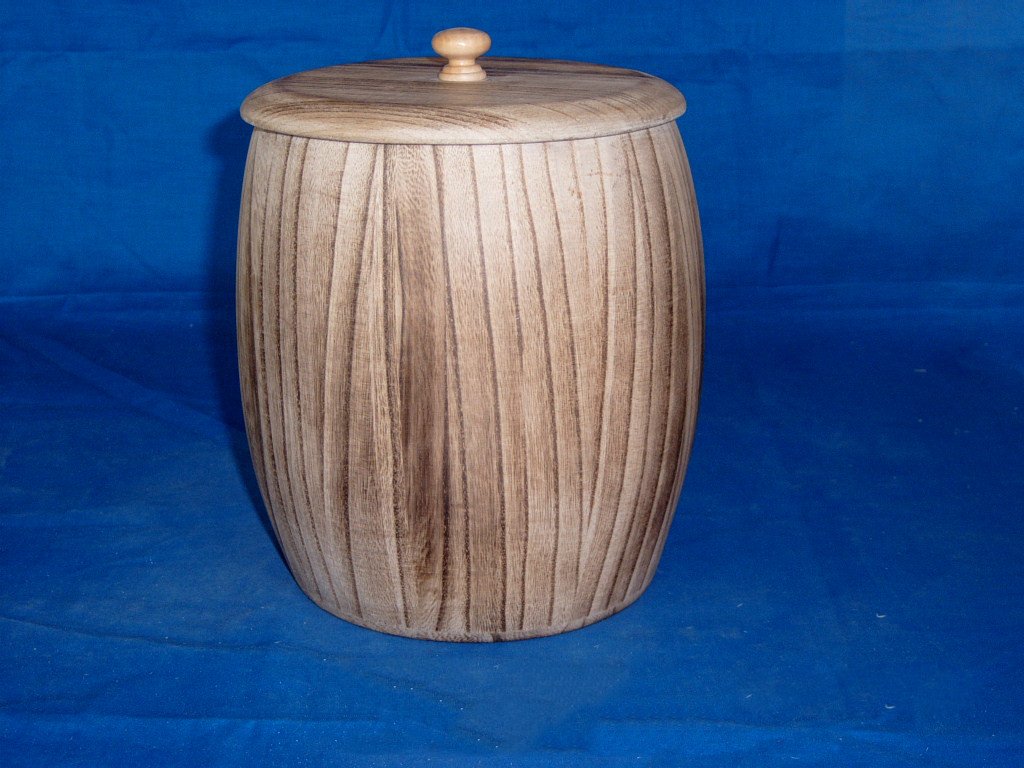 Tall cylindrical natural-wood barrel-shaped wooden box with vertical wood grain and round wooden knob lid